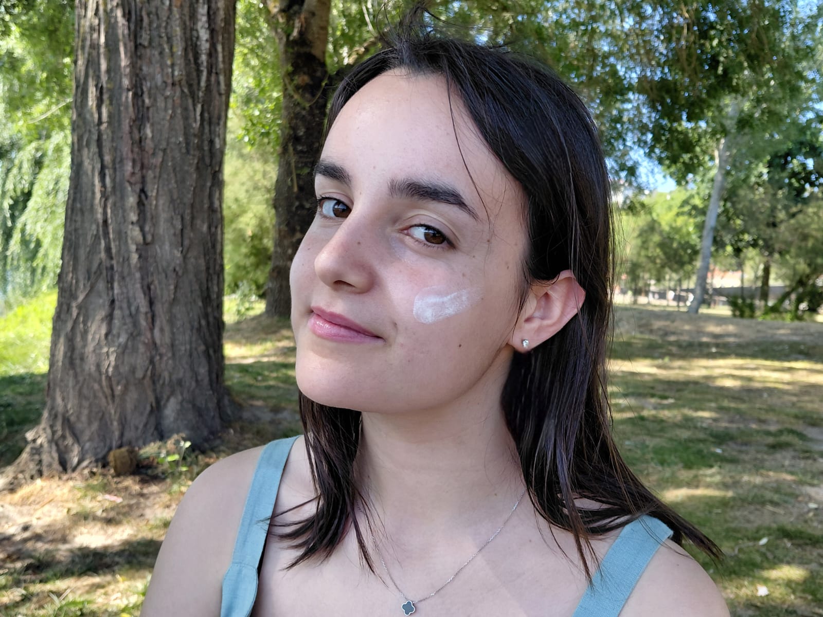 Rosto com protetor solar aplicado na bochecha, num parque